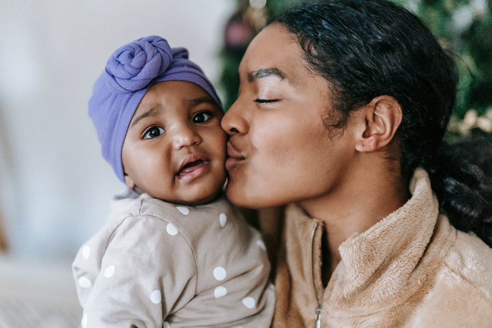 Mother kissing her baby's cheek, a tender fourth trimester moment